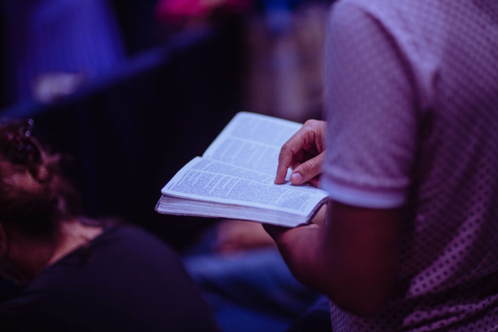 Open Bible and praying hands in peaceful morning light representing daily prayer life